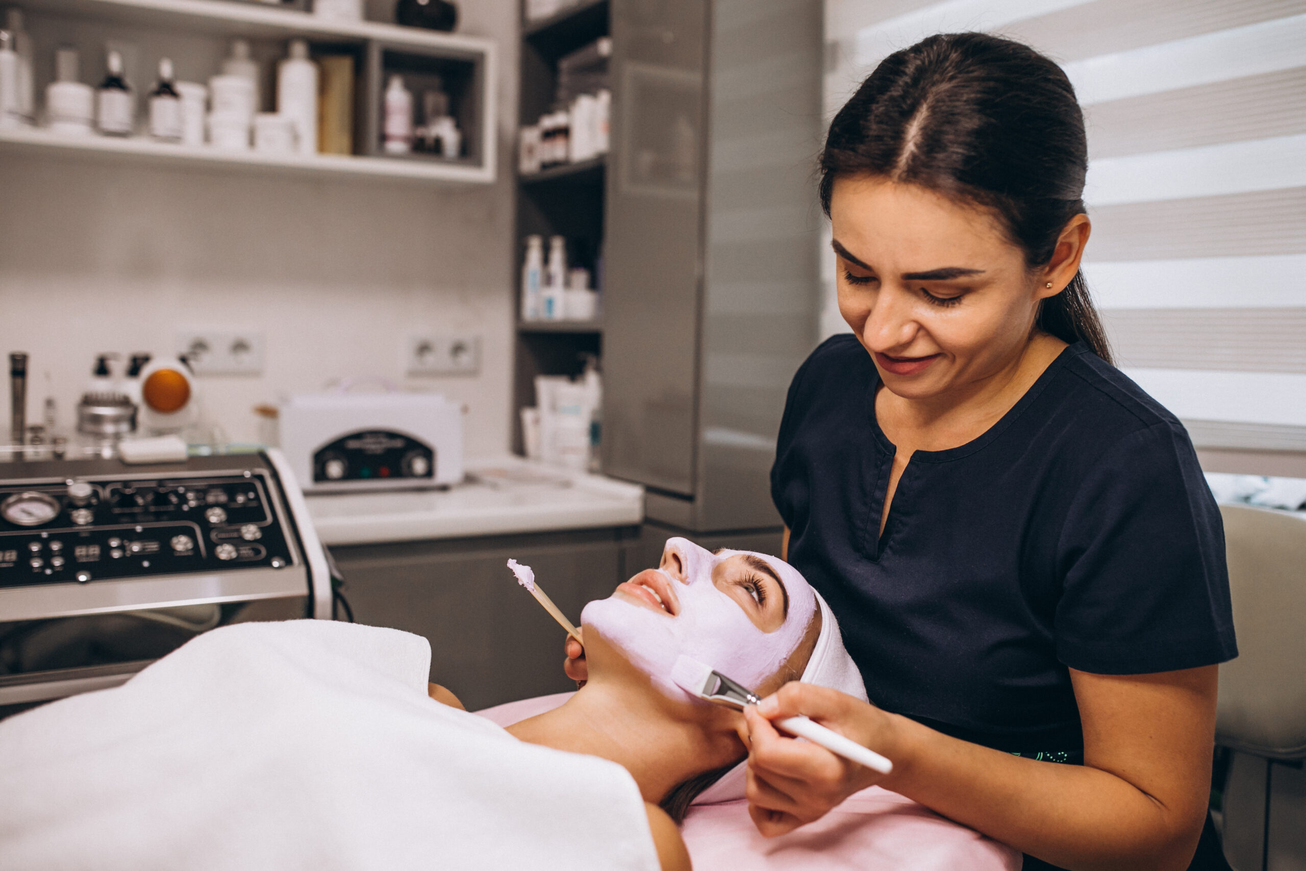 cosmetologist applying mask on a face of client in a beauty salon